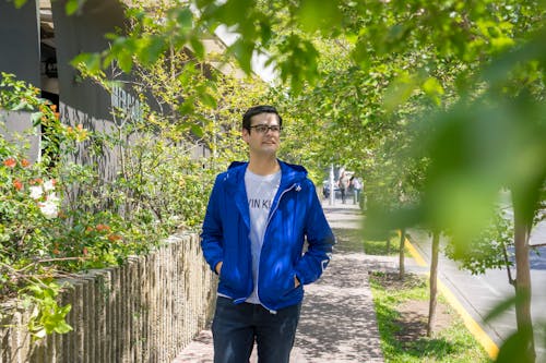 Man in a Blue Jacket Near Green Leaves