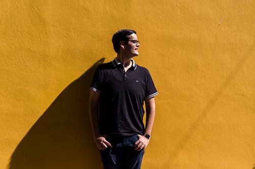 Man in Casual Wear Leaning on Yellow Wall