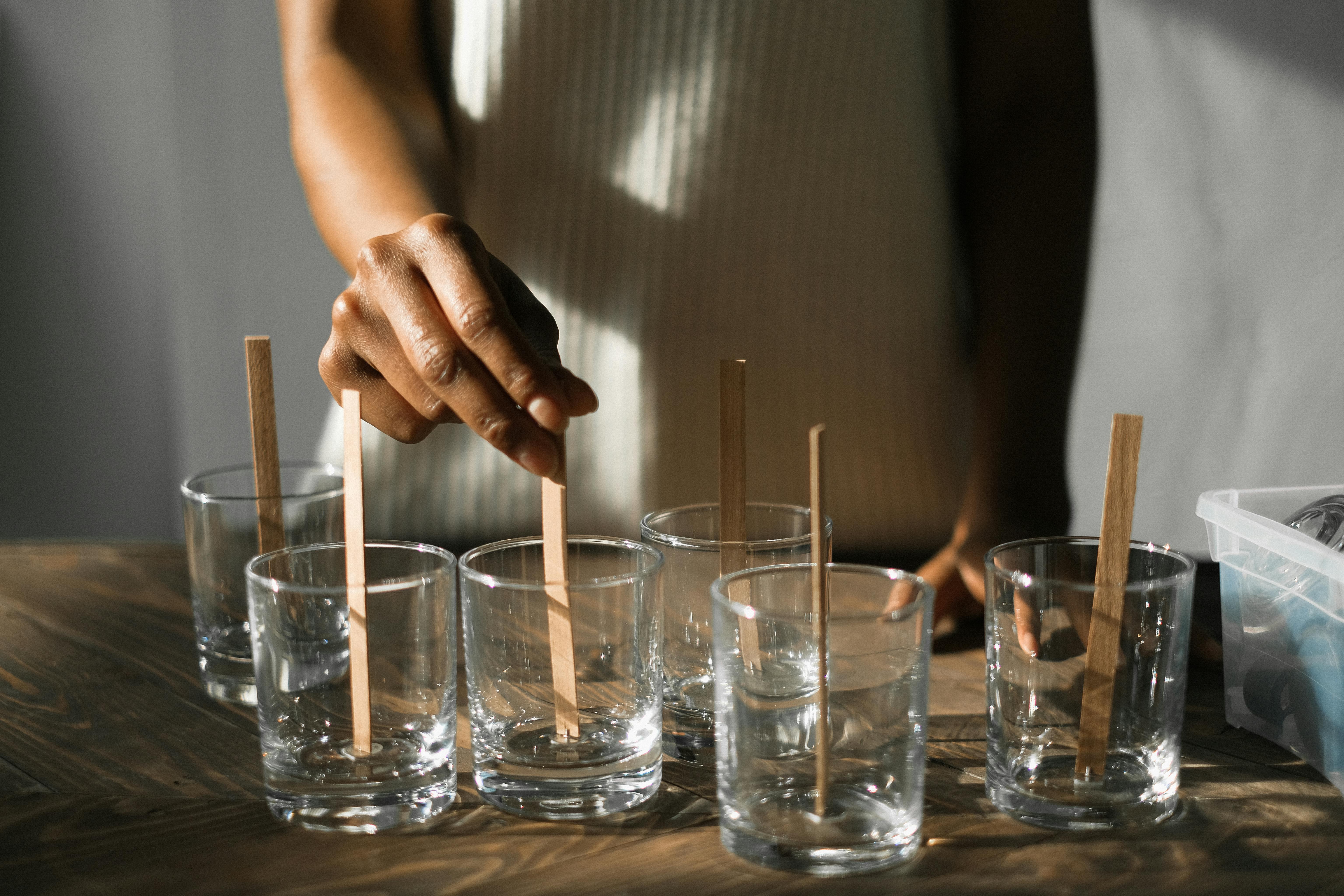 crop black woman putting wicks into candle molds