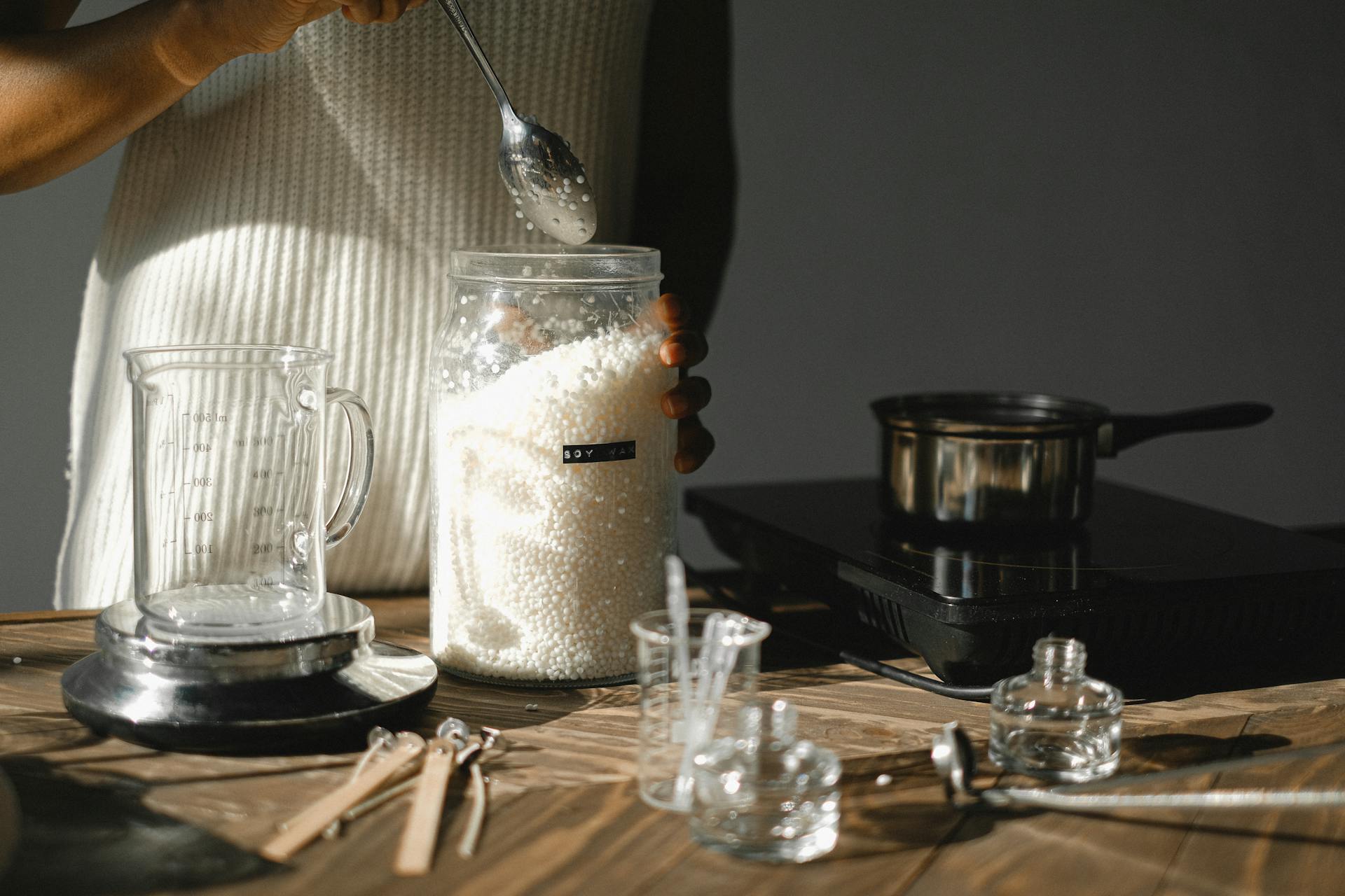 Crop black woman with jar of wax pellets