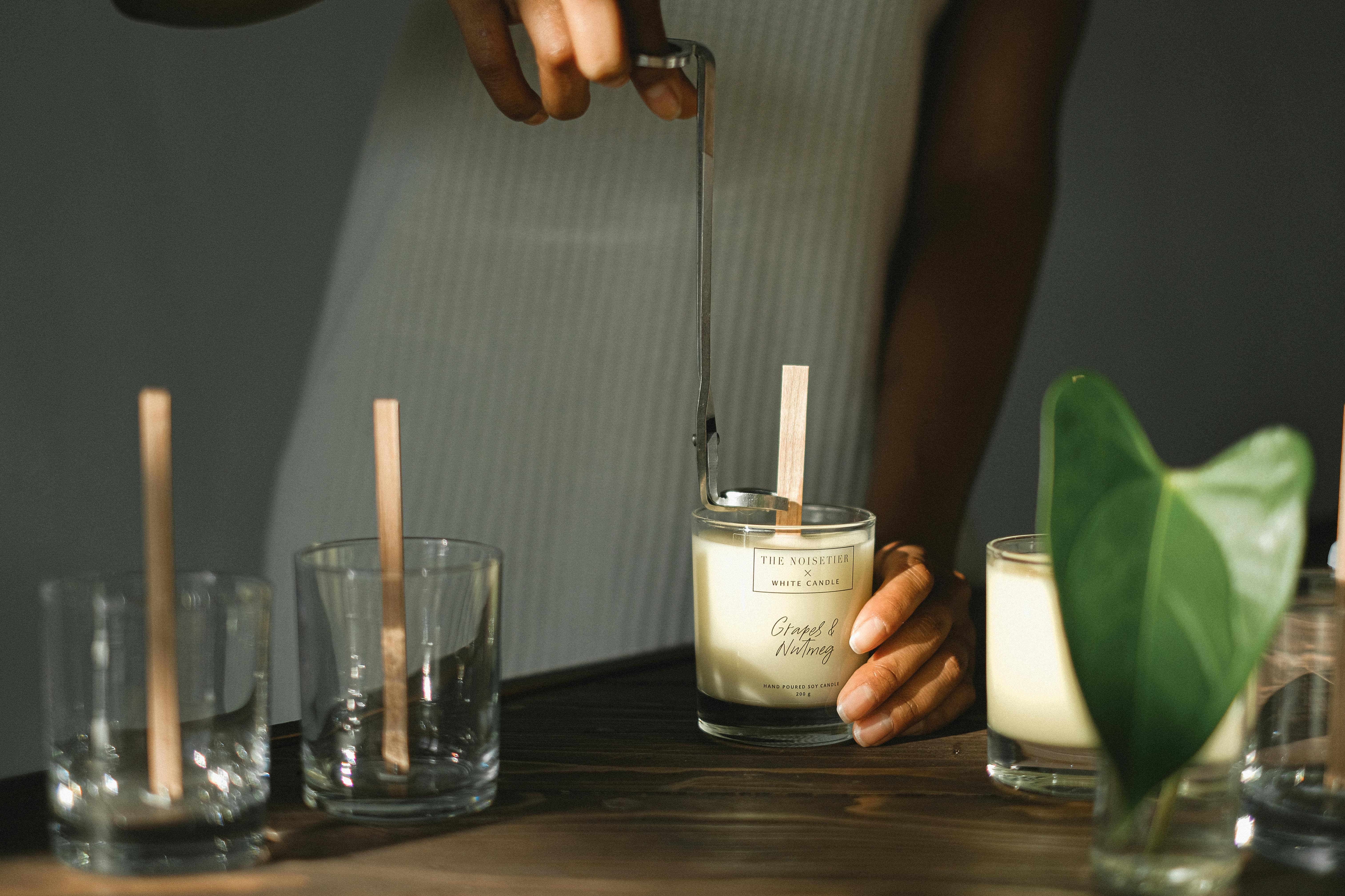 crop black woman with trimmer preparing candles with wicks