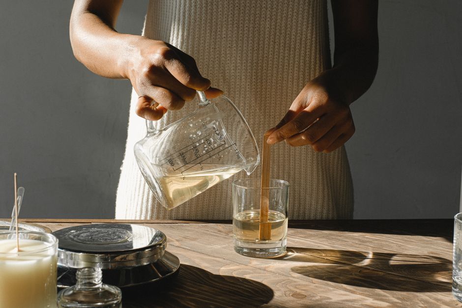A chandler pours melted wax from a glass beaker into a mould — photo by Anna Shvets on Pexels