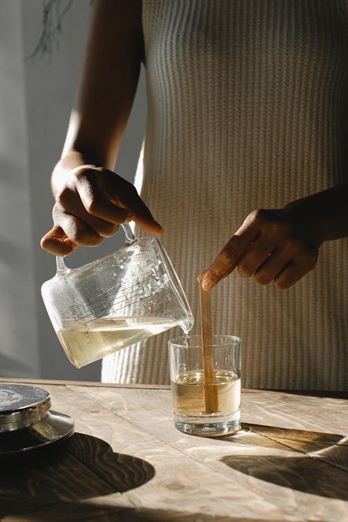 Female Candle Maker Pouring Melted Orange Wax Into The Glass With Glued  Wooden Wick And Measure It On Digital Scale. Wearing Protective Work Wear. Candle  Making Process Stock Photo, Picture and Royalty