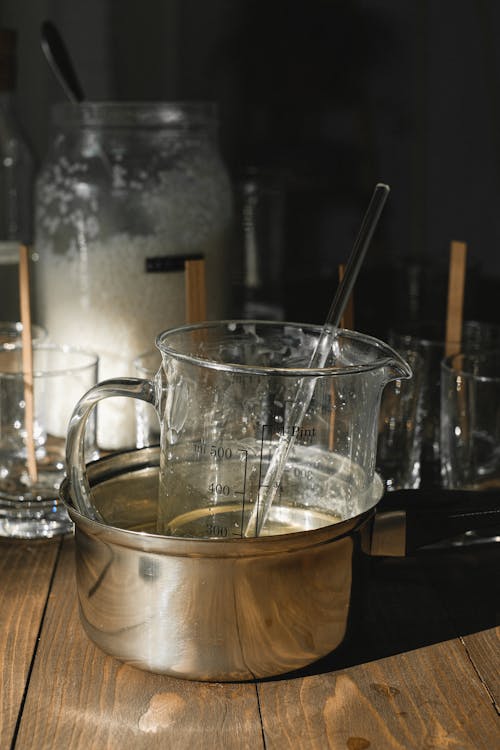 Glass jug with melt wax on wooden table