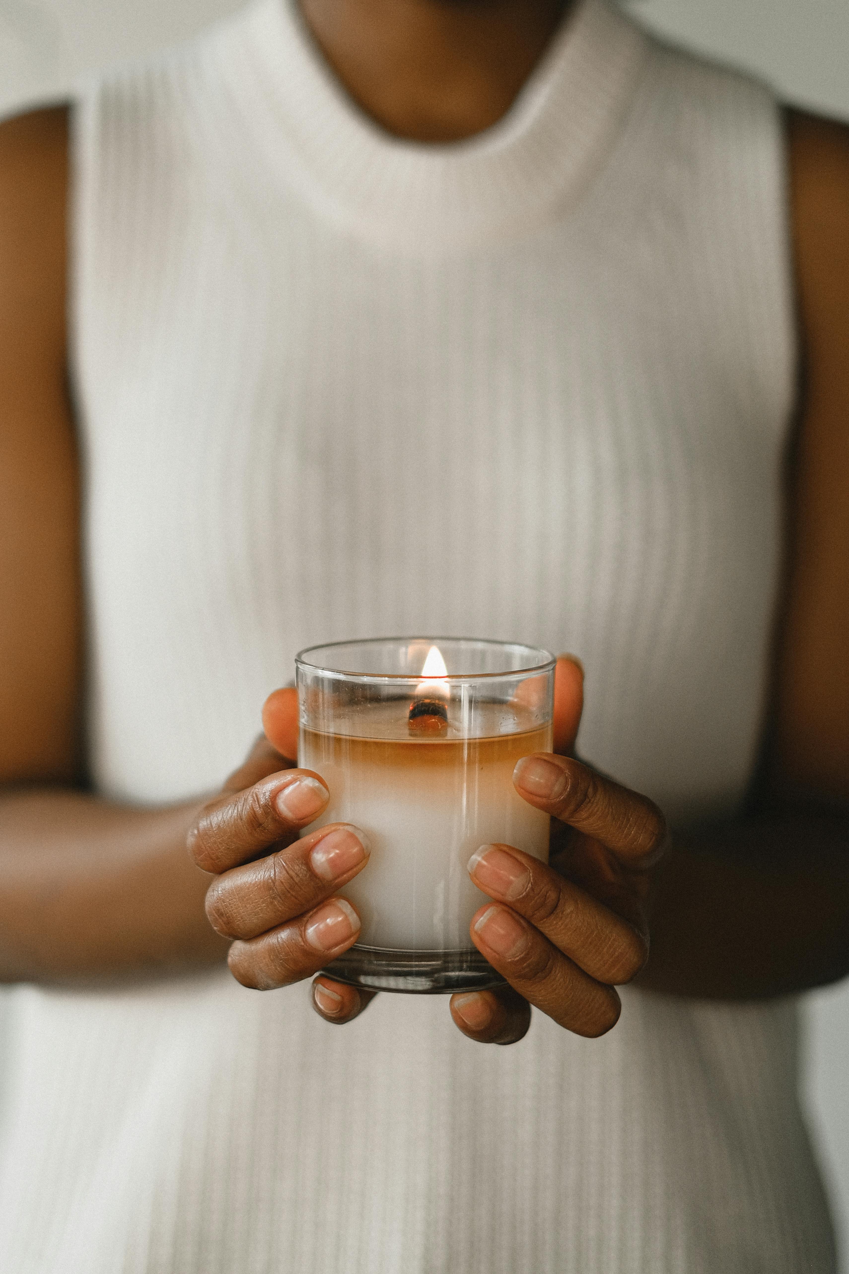 unrecognizable ethnic woman with burning candle in glass