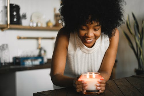 Cheerful black woman with burning candle at home