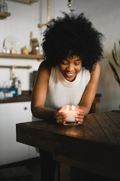 Ethnic woman with aromatic candle at home