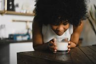 Tranquil African American female enjoying aromatic scent of candle in glass during aromatherapy at home