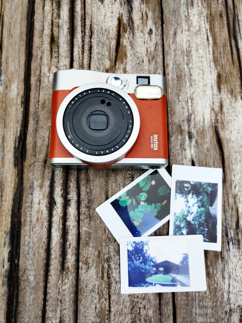 White and Red Camera on Brown Wooden Table