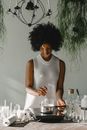 Tranquil black woman making candles on cooker in workshop