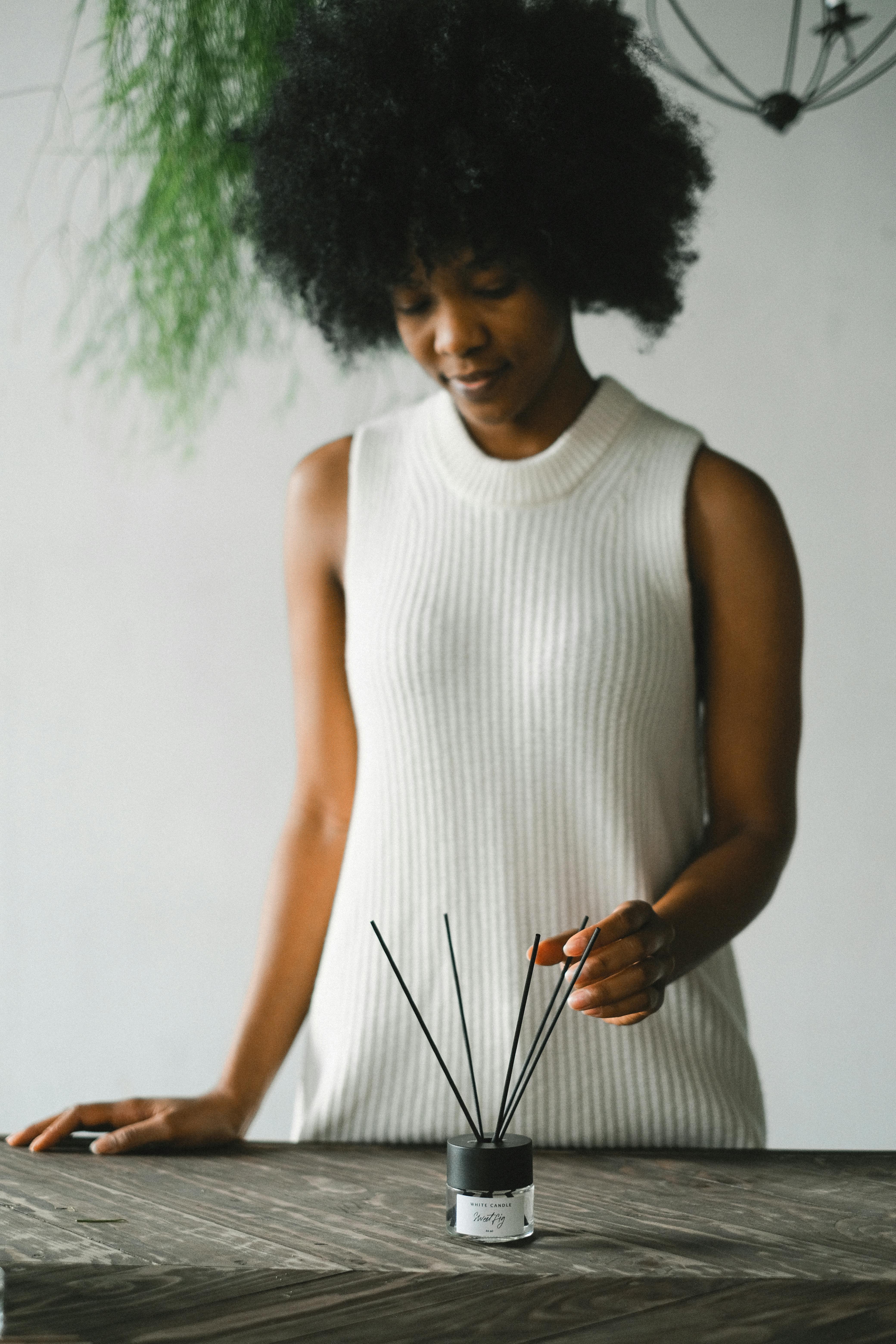 serene black woman with incense sticks at table