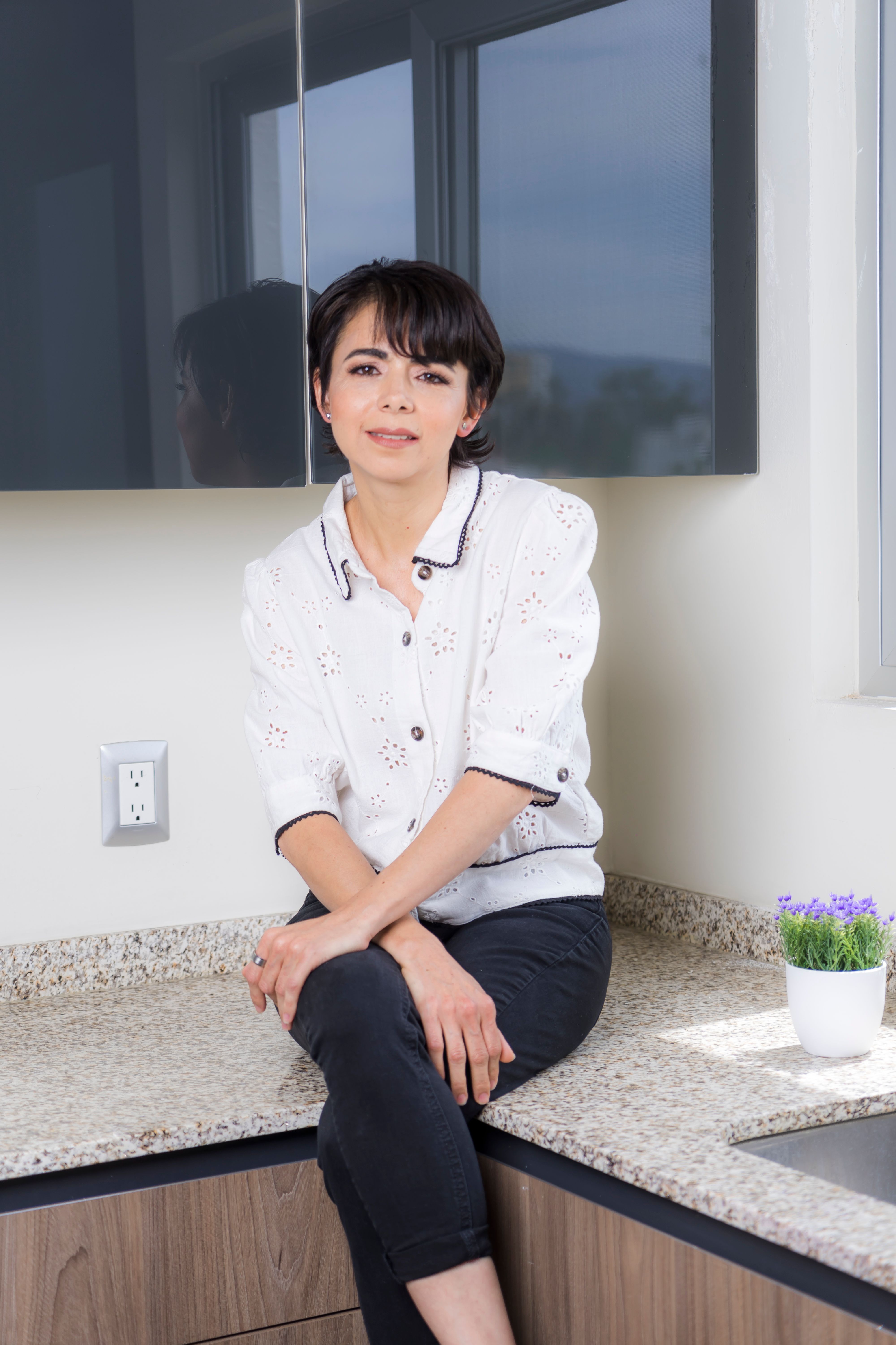 A relaxed woman sits on a kitchen counter, creating a homely and stylish vibe.