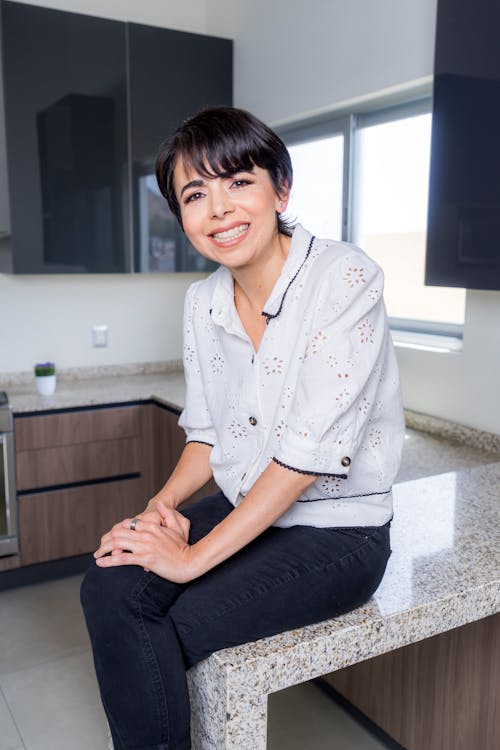A Smiling Woman Sitting on the Kitchen Counter