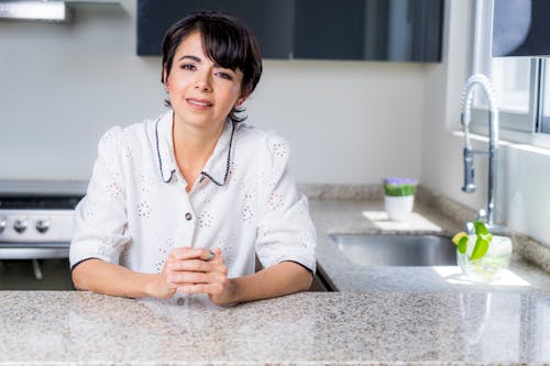 A Smiling Woman Leaning on the Kitchen Counter