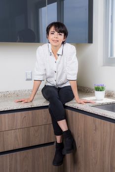 一位穿着休闲装的西班牙裔女性坐在厨房柜台上，散发着温暖又时尚的气息