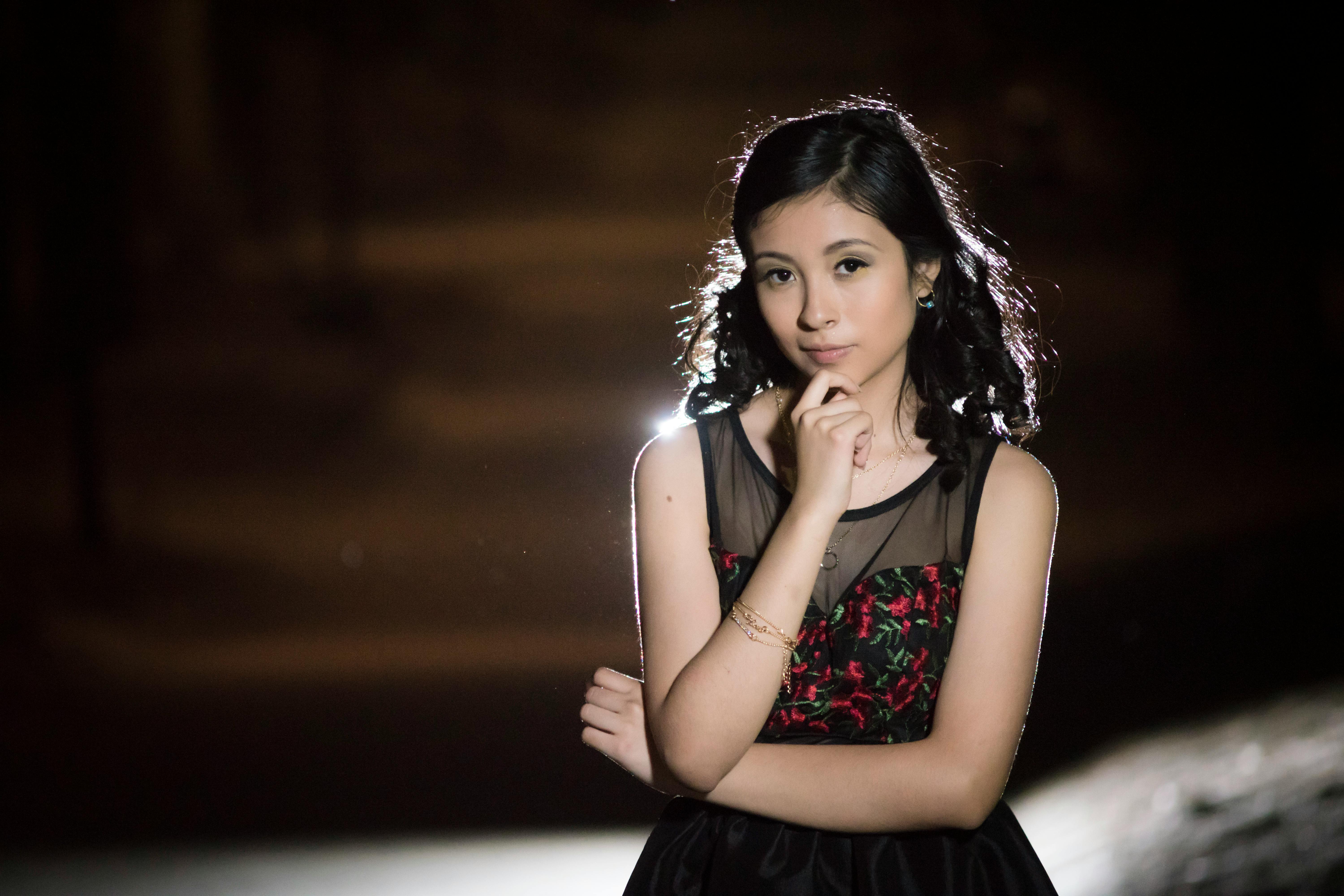 Captivating outdoor portrait of a teenager in a black dress during a night photoshoot.