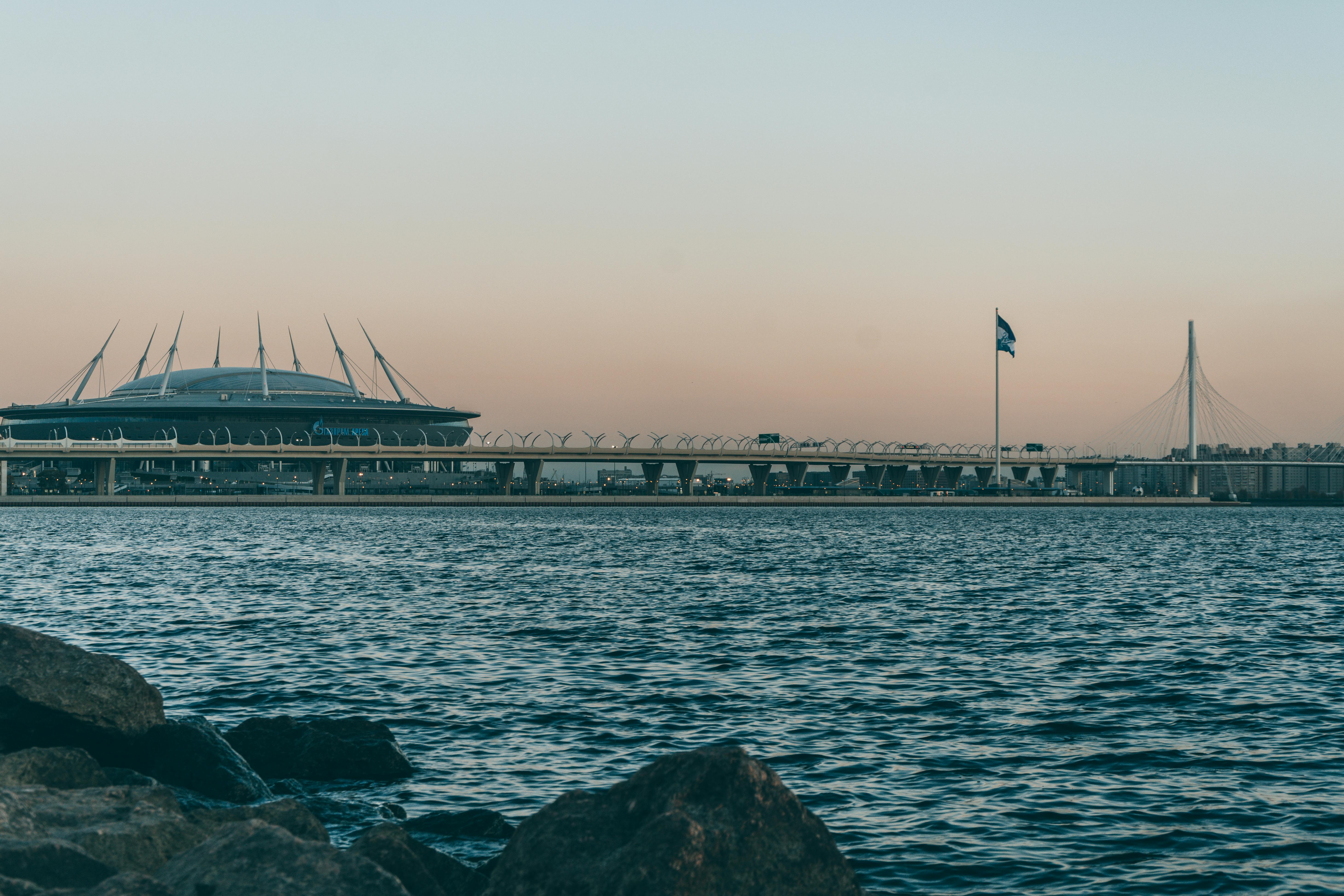 stadium against bridge and rippled river in evening city