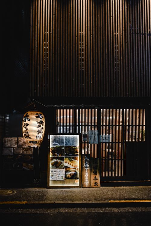 Free Dimly lit street view of a charming urban restaurant entrance adorned with traditional lanterns. Stock Photo