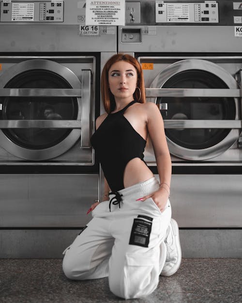 Attractive woman in street wear siting on haunches in laundry