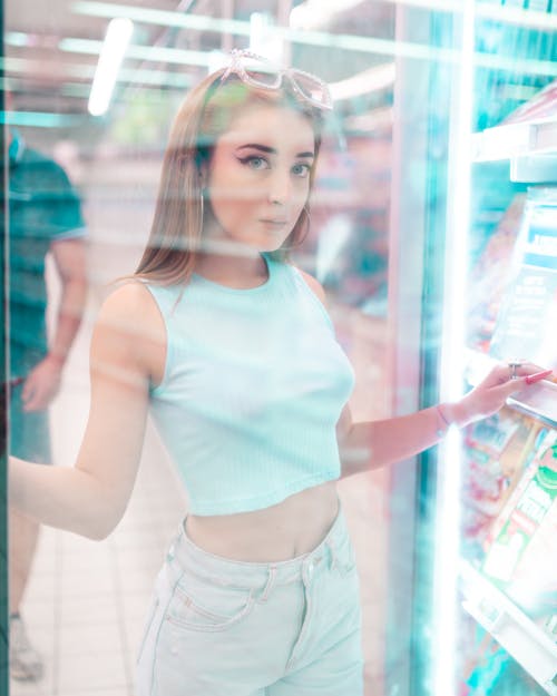 Free Pretty woman looking at camera through refrigerator glass door Stock Photo