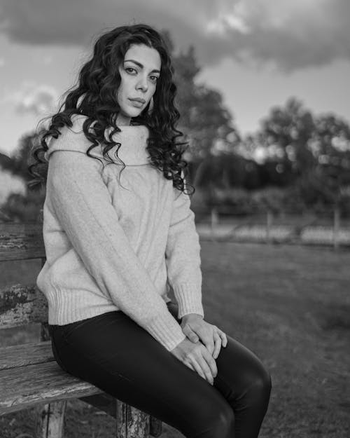 Wistful woman sitting on shabby bench in countryside