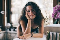 Young female with messy hair and cigarette looking away on blurred background of comfortable modern apartment