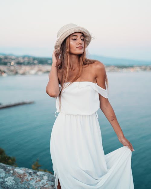 Stylish lady standing on cliff against ocean