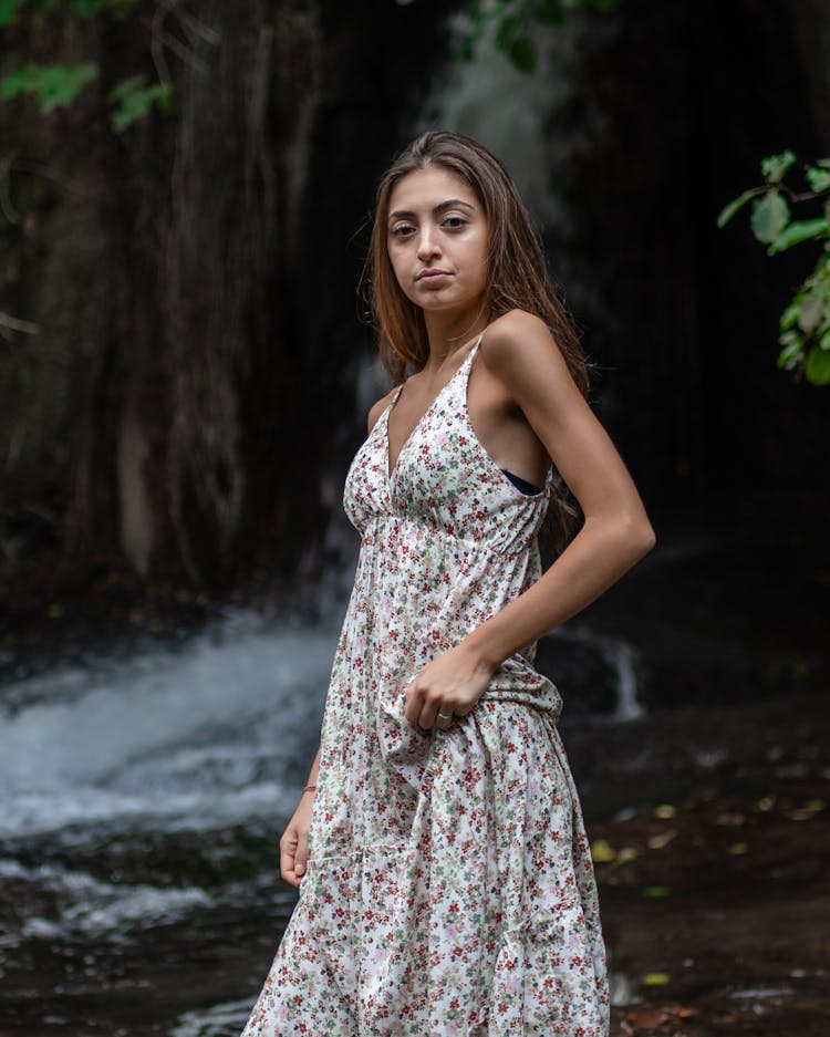 Young Woman Standing Against Waterfall In Forest