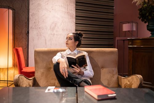 Free Concentrated female with casual hairstyle holding book while sitting on cozy couch and looking away Stock Photo