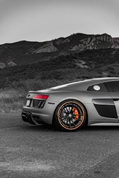A sleek Audi R8 parked against a dramatic mountain background, showcasing its striking wheels and design.