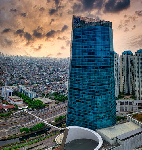 Picturesque cloudy sunset sky over modern megapolis with futuristic skyscrapers with glass walls and asphalt roads