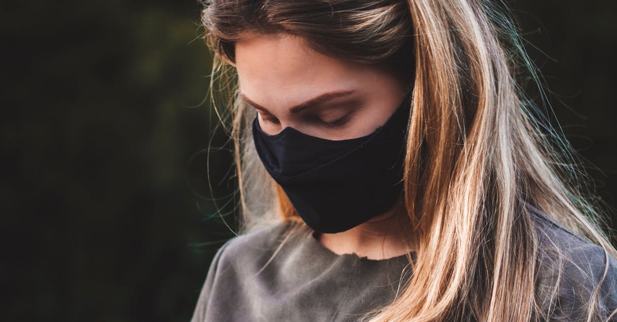 Photo by Ryan Pilato Woman wearing a mask and sunglasses uses smartphone outdoors