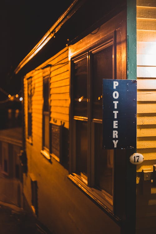 Facade of wooden building with signboard with inscription illuminated by street lamp at night time