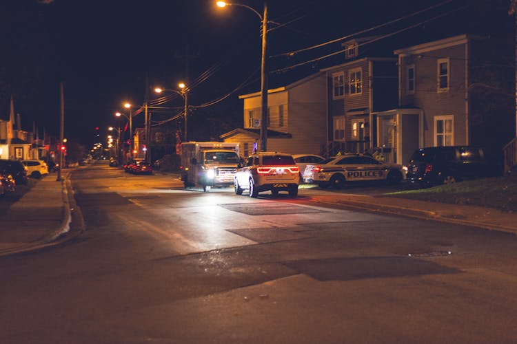 Cars Driving On Street In Suburb At Night