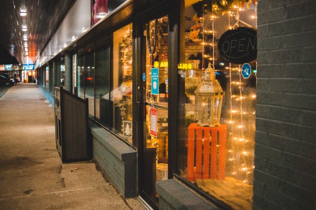Petite boutique de centre-ville éclairée en soirée avec décorations lumineuses