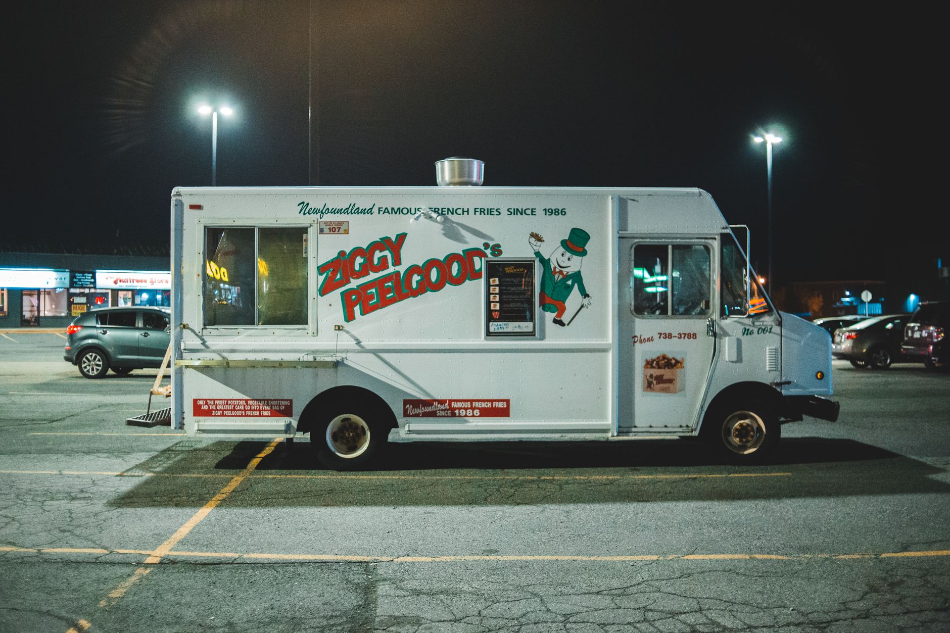 Commercial car with inscriptions parked in parking lot on street at night time
