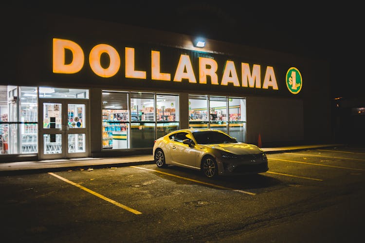 Modern White Car Parked Near Shop At Night