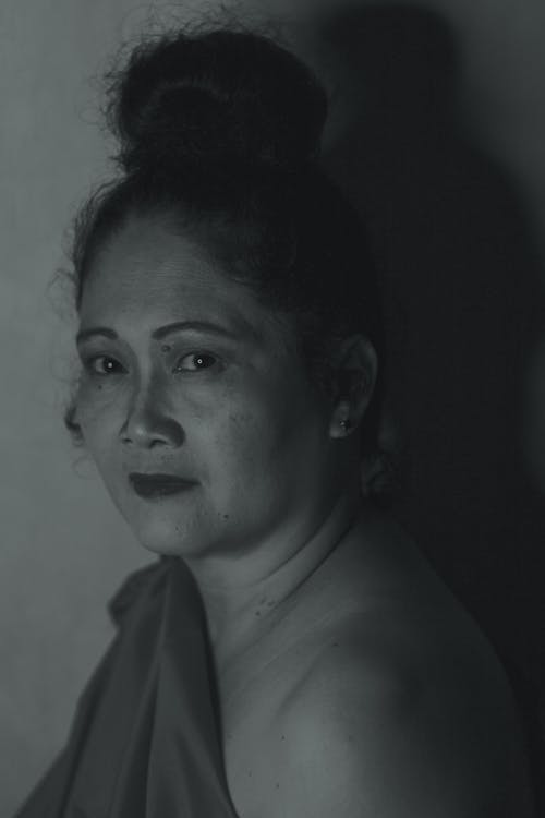 Free Black and white portrait of tranquil middle aged Asian female with hair bun looking at camera Stock Photo