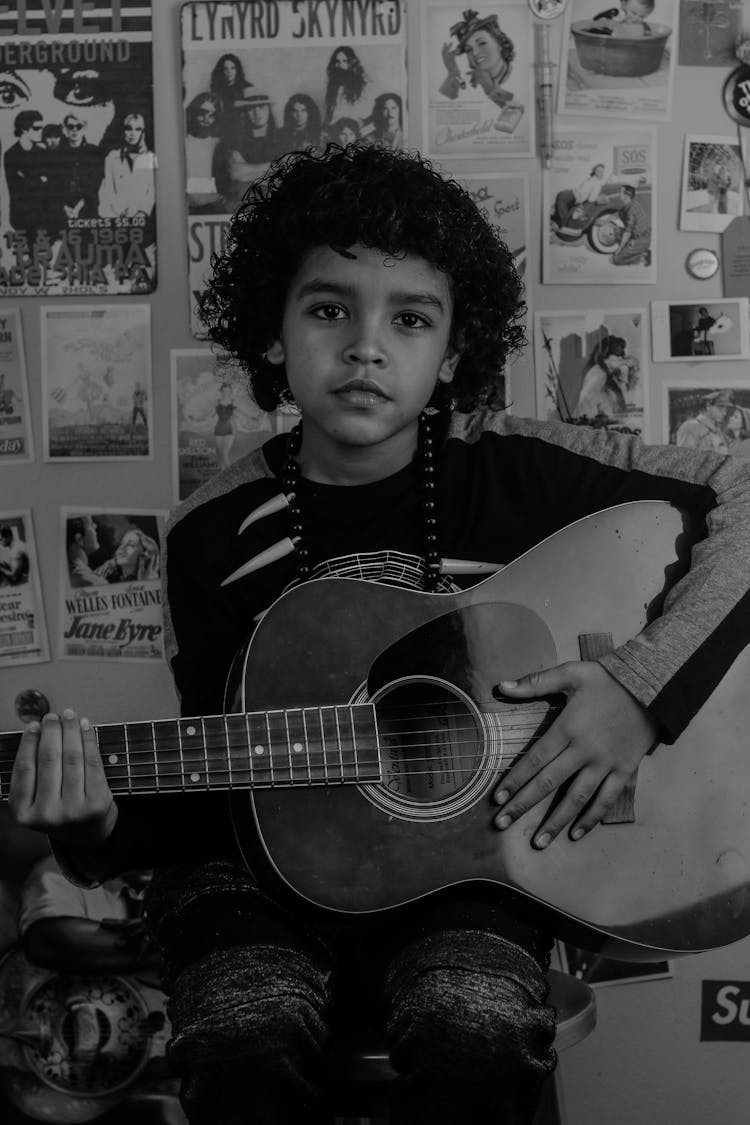 Black Musician With Classic Guitar Against Wall With Photos