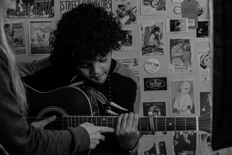 Crop Teacher Interacting With Black Pupil Playing Guitar