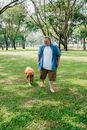 一个人赤脚和金毛猎犬走在阳光明媚、郁郁葱葱的公园里
