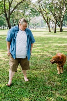 在绿树环绕的风景公园里，一个男人和他的金毛猎犬正享受着阳光