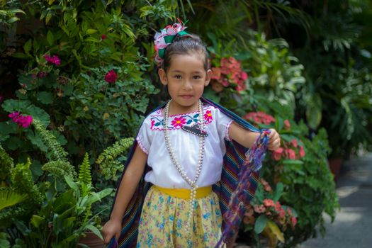 Young girl posing in traditional Mexican attire with floral print and accessories.