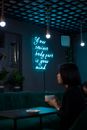 Young woman sitting in cafe with life quote on wall