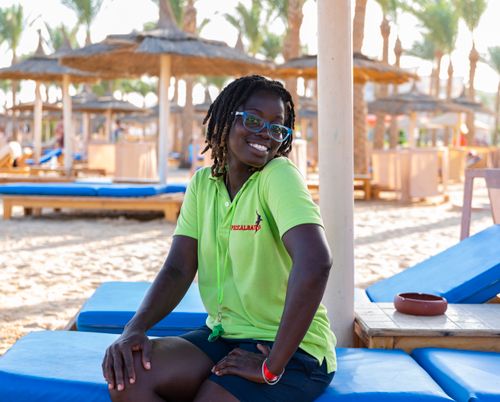 Free A cheerful woman enjoying a sunny day at a tropical beachside resort, showcasing relaxation and happiness. Stock Photo