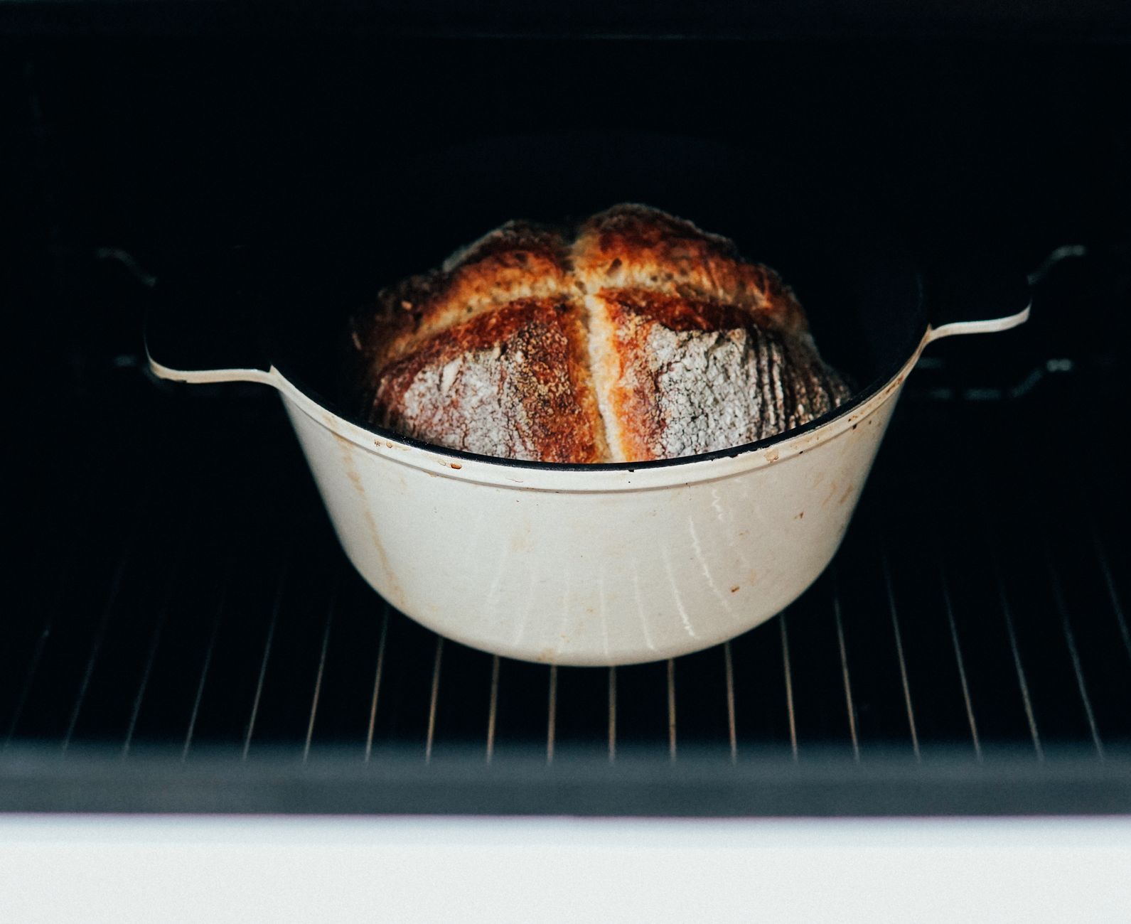 Freshly baked dutch oven bread with golden crust cooling on wire rack