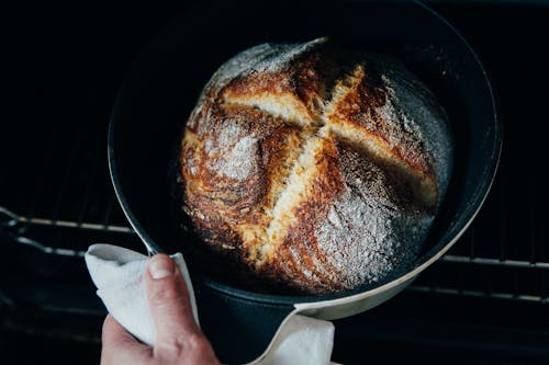 Free From above of crop anonymous chef pulling out fresh crispy bread from oven Stock Photo