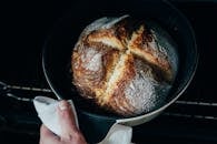 From above of crop anonymous chef pulling out fresh crispy bread from oven