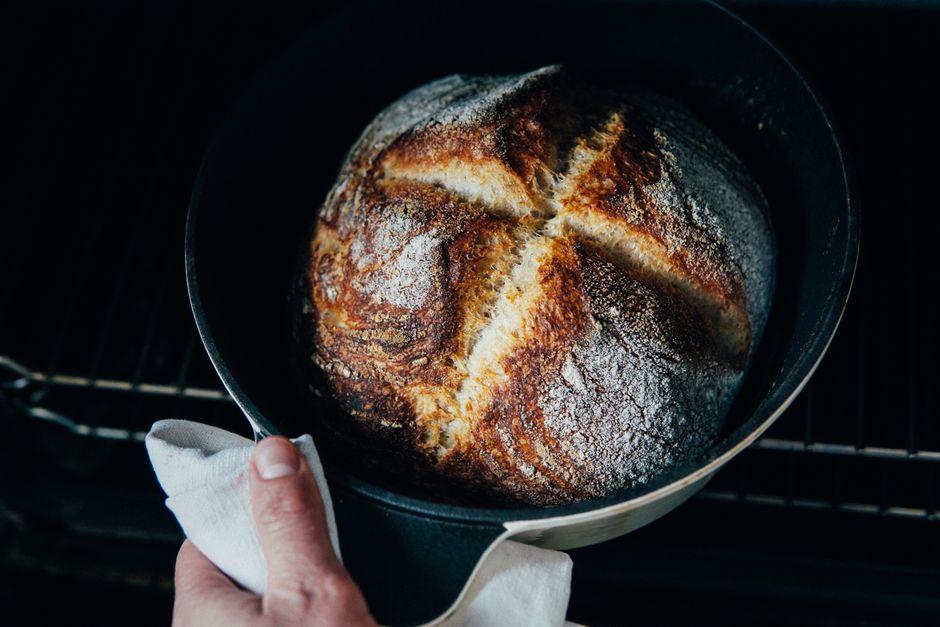 From above of crop anonymous chef pulling out fresh crispy bread from oven