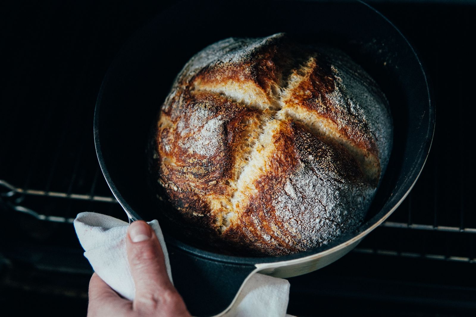 Mains sortant une pâte au levain d'une cocotte avant enfournement